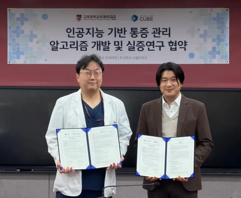 Representatives of Korea University College of Medicine and StellarCube holding signed agreements in front of a banner reading 'Agreement on the development and demonstration study of an AI-based pain management algorithm'